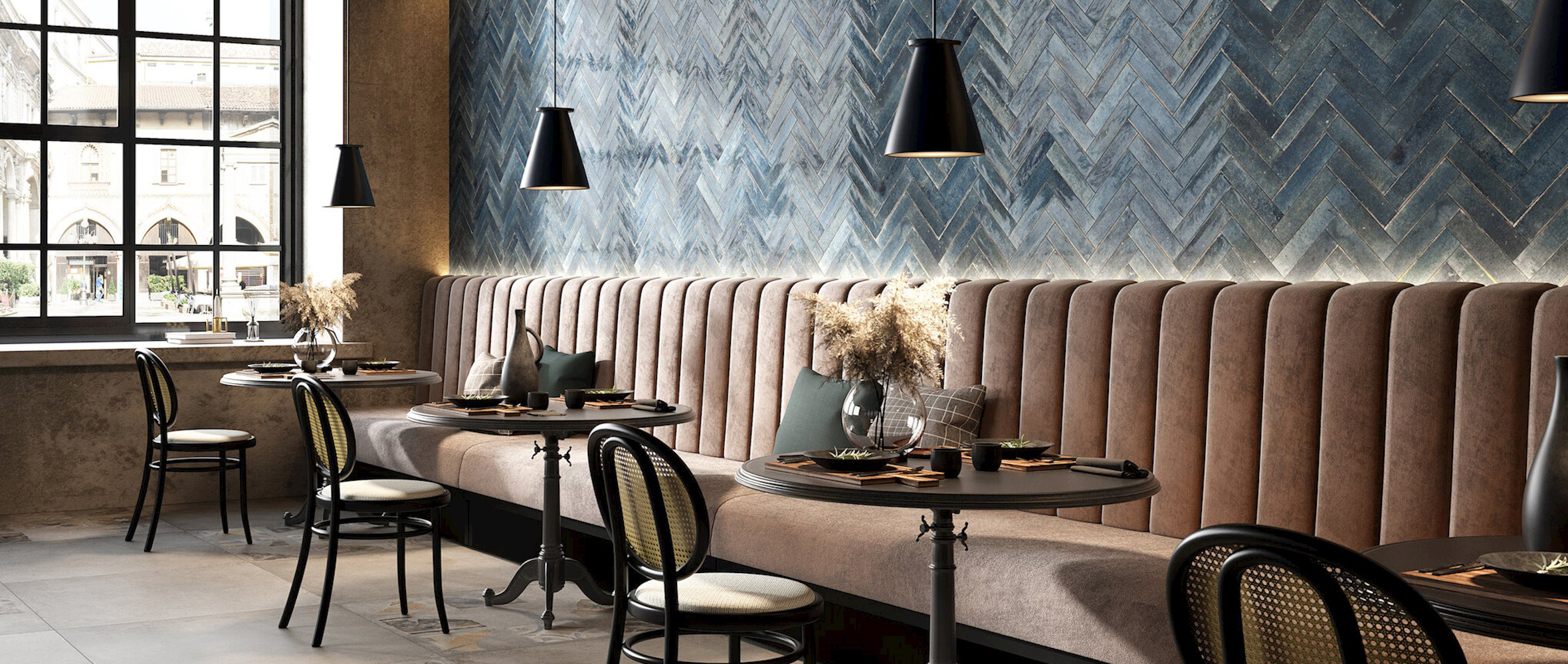 Moderni maalaisromanttinen sisustus ravintolassa, rottinkiset tuolit, kalanruotoladonta kiiltävillä sinisillä laatoilla, mustat ikkunat.