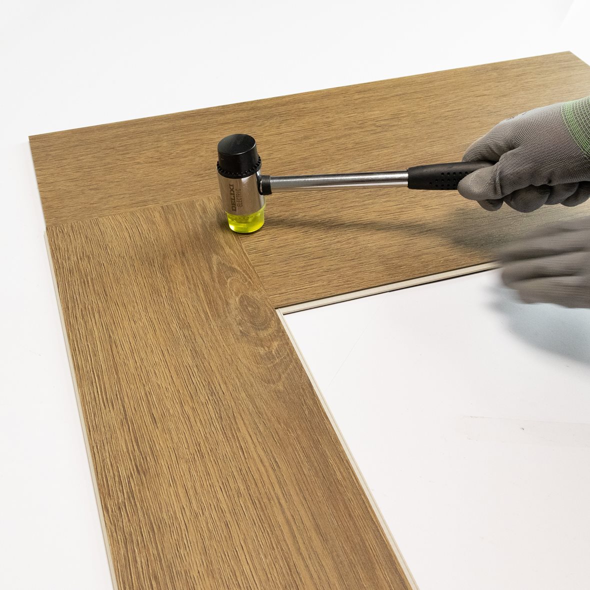 Pontillisen kalanruotovinyylilankun asennus. Lyhyen sivun pontti viedään kohdalleen ja lukitaan kumivasaran napautuksella.